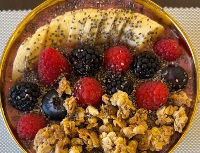 Bowl de fruits rouges, banane, granola et graines de chia dans un bol doré, Kuma Lounge Marrakech